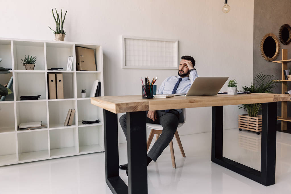 Бизнесмен сидит за столом с ноутбуком - Фото, изображение