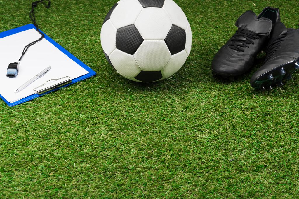 кишеня з футбольним м'ячем і черевиками на траві
 - Фото, зображення