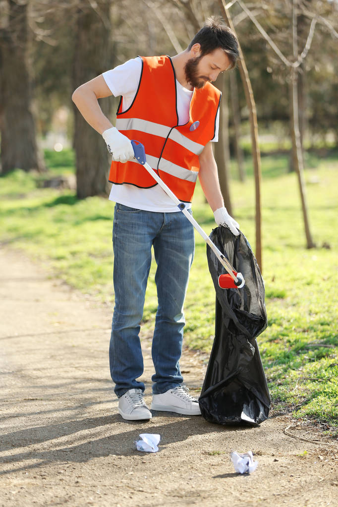 Joven voluntario recogiendo basura en el parque
 - Foto, Imagen