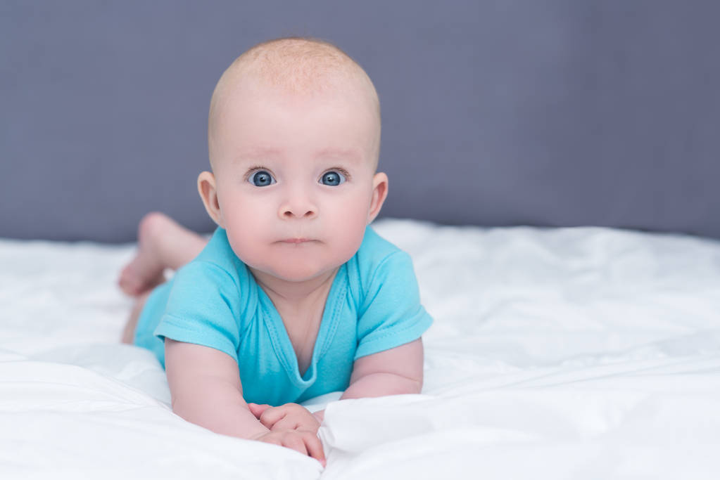 entzückendes Baby Mädchen oder Junge in blauem Hemd mit großen blauen Augen, indo - Foto, Bild