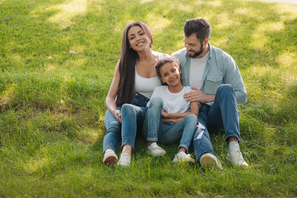 perhe lepää vihreällä nurmikolla
 - Valokuva, kuva