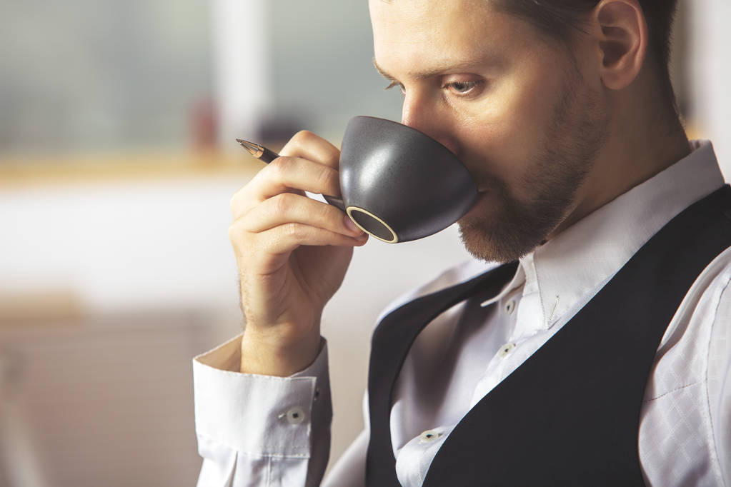 Komea liikemies, joka juo kahvia työpaikalla
 - Valokuva, kuva