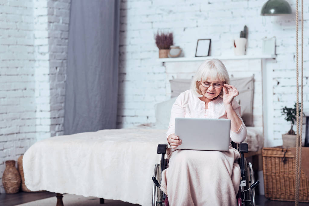 Handicap zaangażowanych starzenia się kobiety za pomocą laptopa w domu - Zdjęcie, obraz