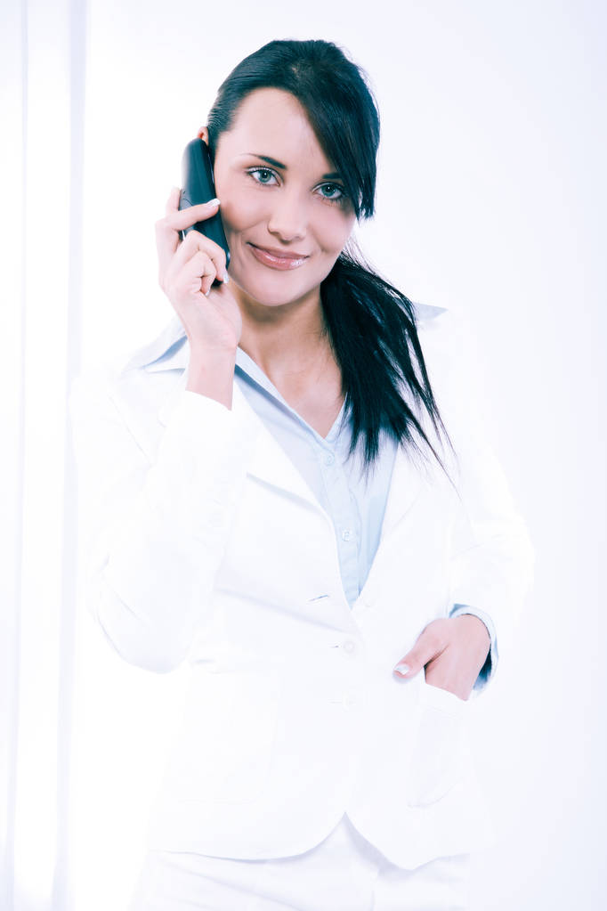 Aantrekkelijke jonge vrouw met onderhandelingen telefonisch in kantoor - Foto, afbeelding