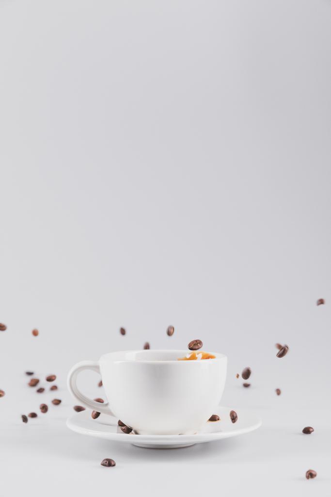kahvikupin kanssa hajallaan kahvinjyvät
 - Valokuva, kuva