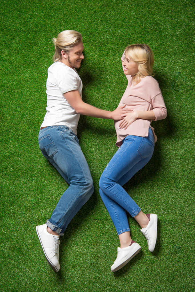 pregnant woman with boyfriend lying on grass - Photo, Image
