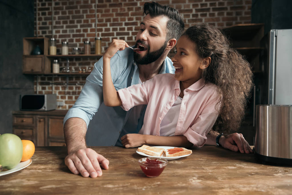 дівчина годує батька варенням
 - Фото, зображення