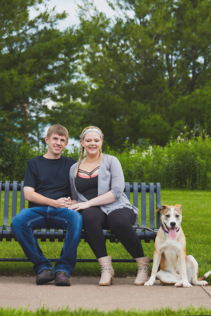 Счастливая пара сидит на скамейке с собакой на поводке
 - Фото, изображение