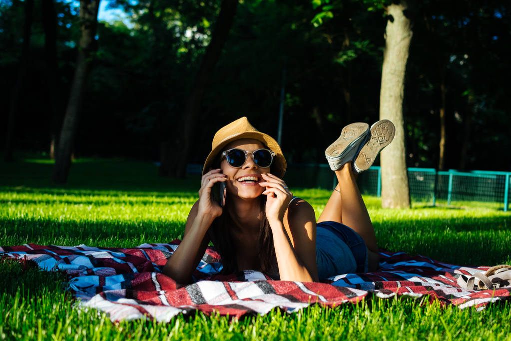 Retrato de una hermosa chica en un parque hablando por teléfono
 - Foto, Imagen
