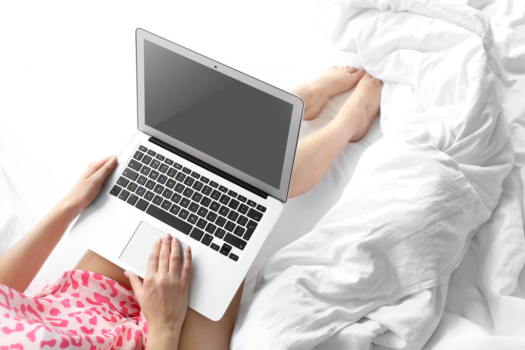 Jeune femme travaillant avec un ordinateur portable sur le lit
 - Photo, image