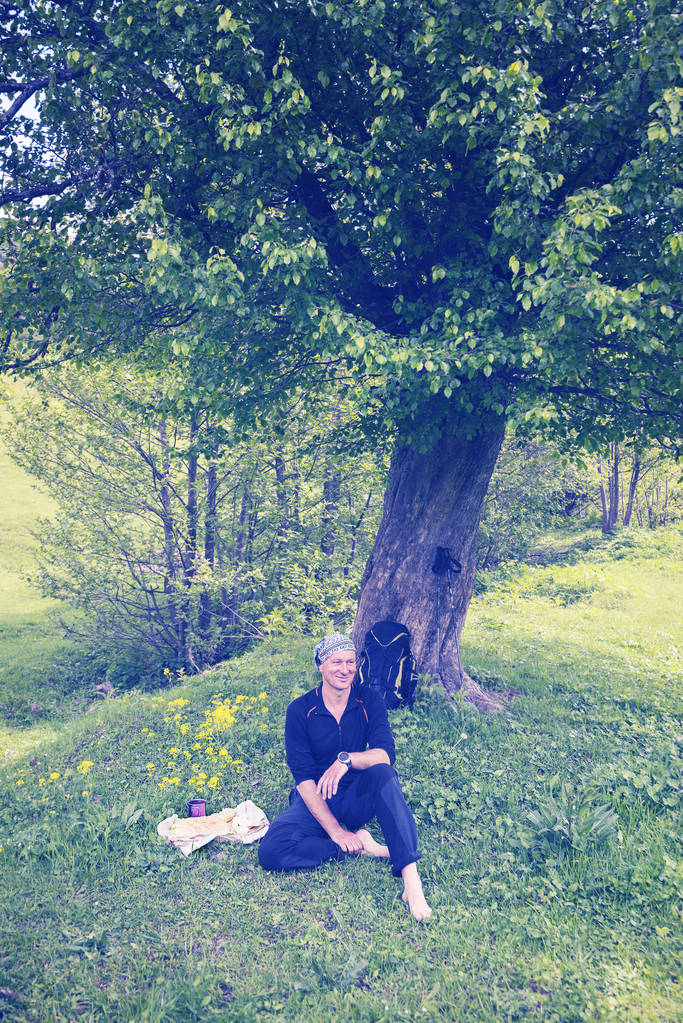 Uomo viaggiatore sorridente, a piedi nudi si rilassa sul prato verde
 - Foto, immagini