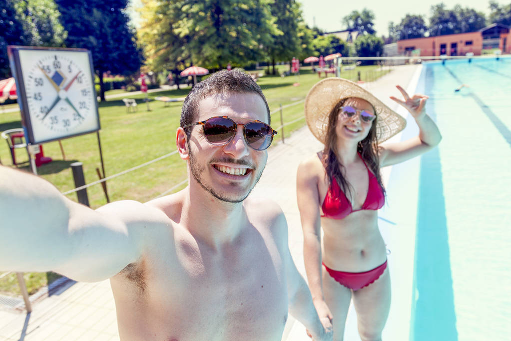 Young liefdevolle paar naast het zwembad neemt een selfie - Foto, afbeelding