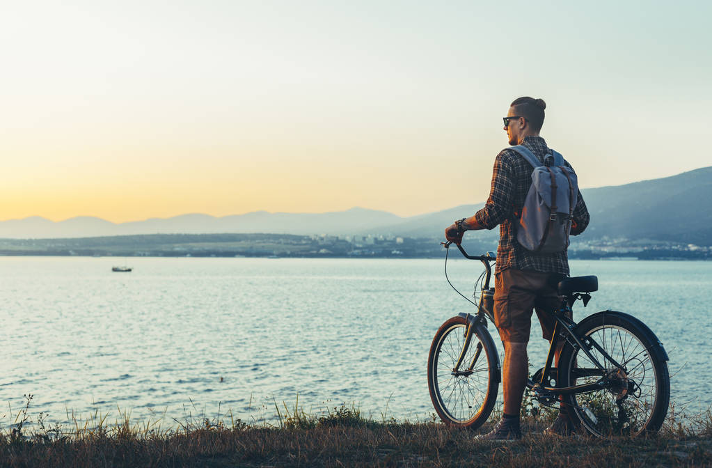 Jonge Man wielrenner permanent met de fiets op de kust en genieten van uitzicht op de zonsondergang vakantie reizen bestemming rusten Concept - Foto, afbeelding