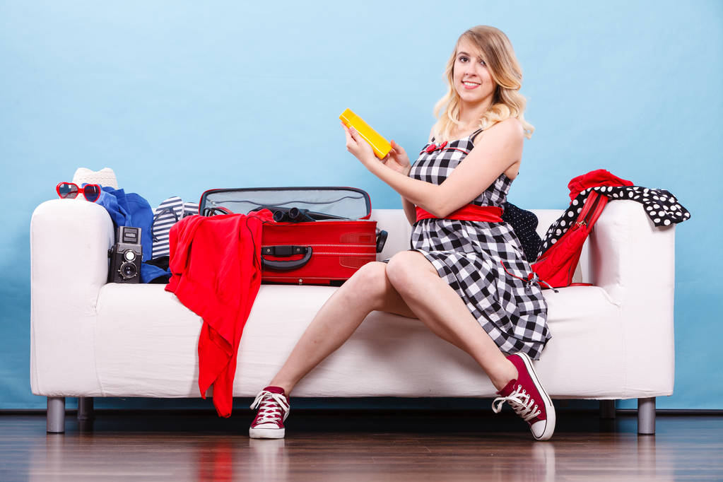 若い女性がソファの上にスーツケースをパッキング - 写真・画像