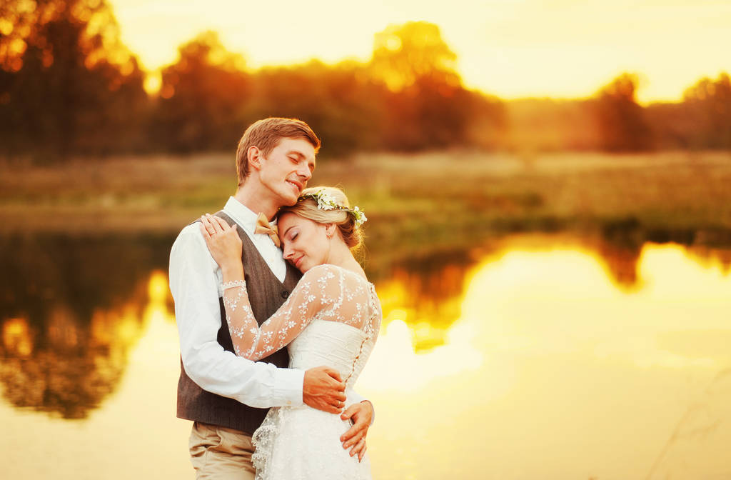 Sposi che si abbracciano sullo sfondo rosso del tramonto
 - Foto, immagini