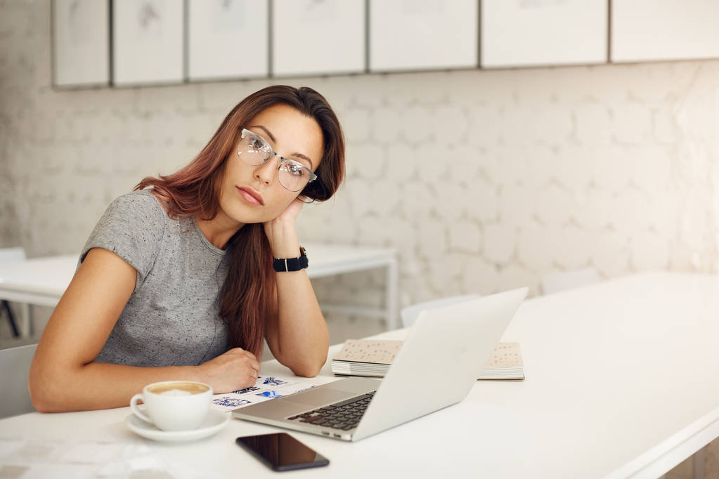 Empreendedora mulher executando uma loja online de sucesso usando laptop usando óculos em um estúdio espaçoso ou café. Conceito freelance
. - Foto, Imagem