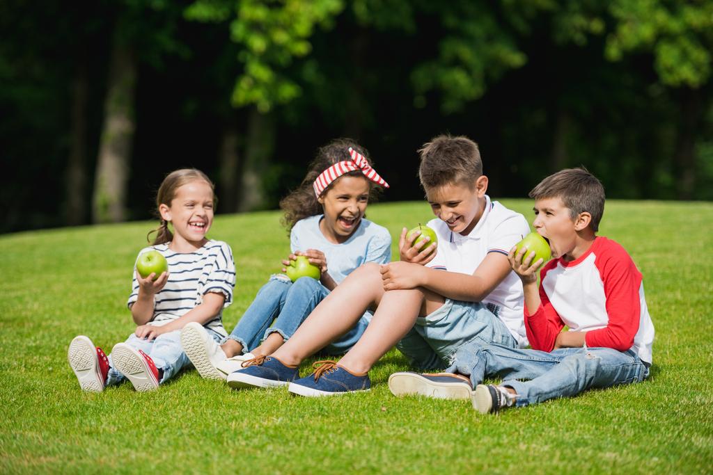 Children eating apples in park - Photo, Image