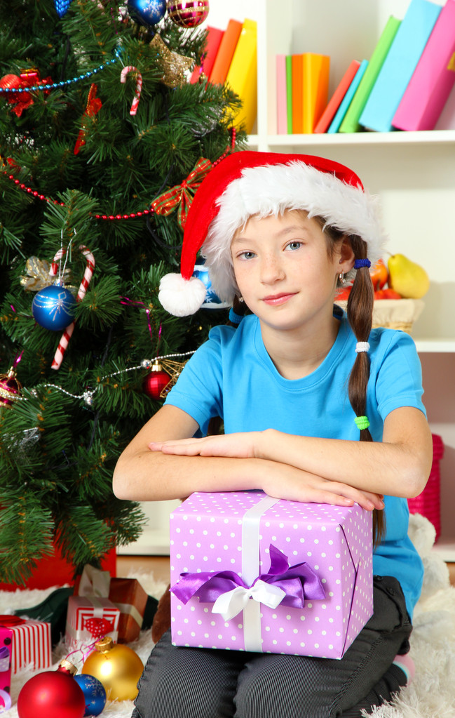 ギフト ボックス クリスマスの木の近くを保持している小さな女の子 - 写真・画像