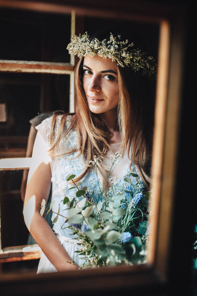 nevěsta v krásné modré šaty a věnec z bílých květů, které drží kytici fialové květy a eukalyptus - Fotografie, Obrázek