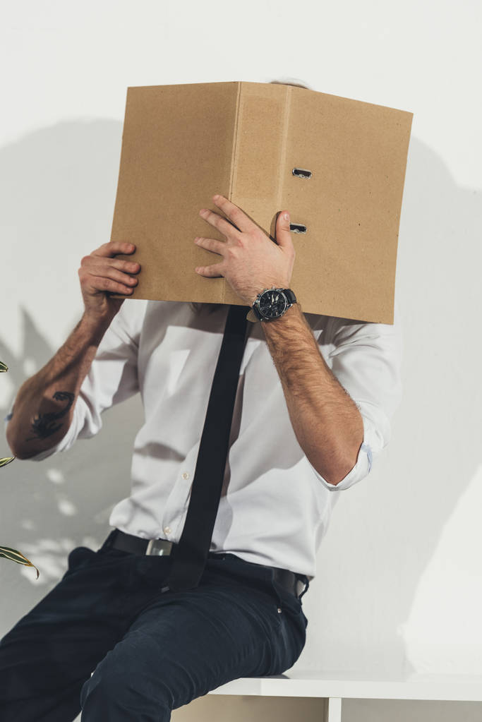 Бизнесмен прячет лицо с папкой
 - Фото, изображение