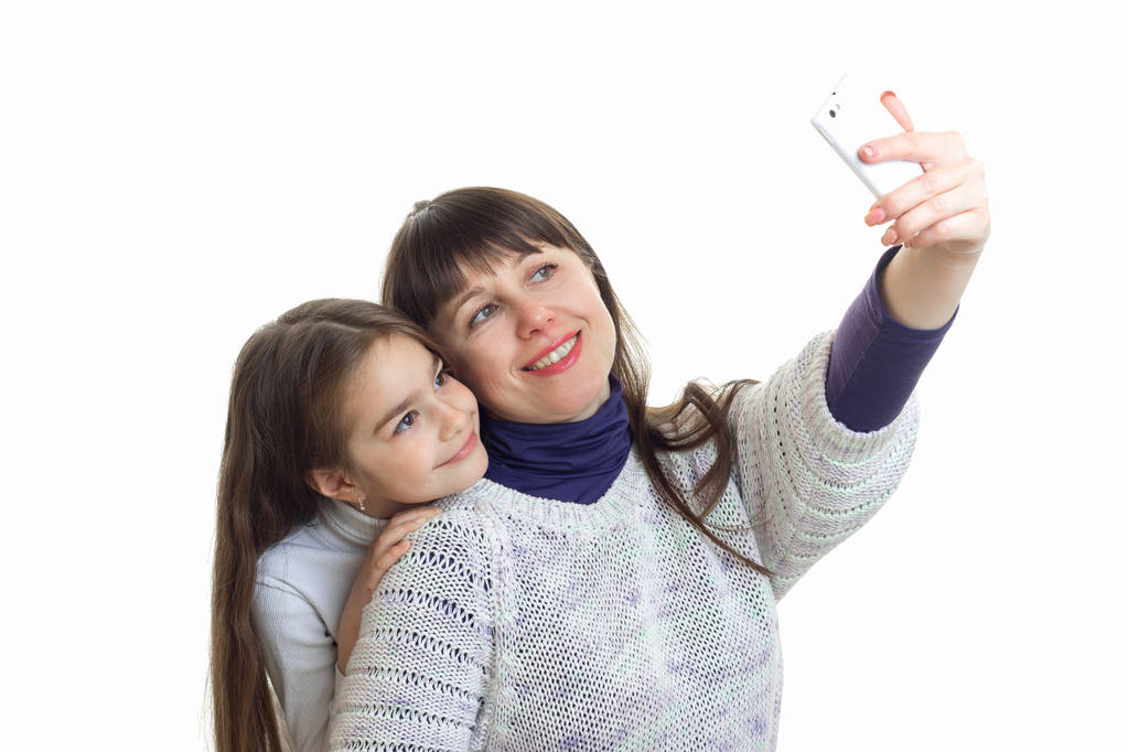 若いお母さんの笑顔し、彼女の娘と携帯電話で写真を作る - 写真・画像