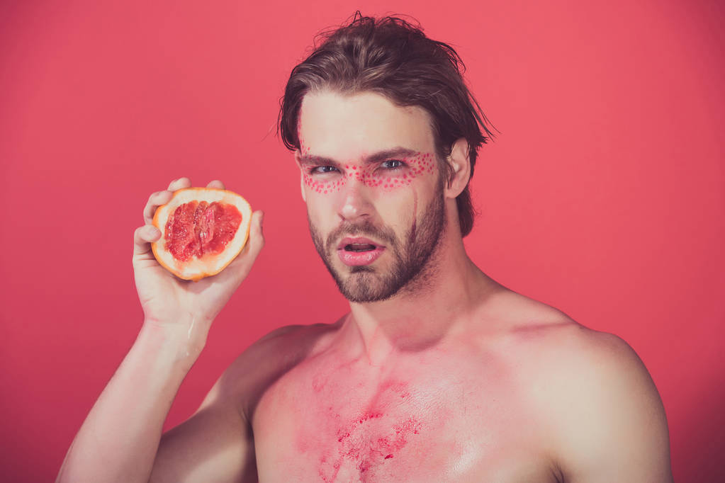 красивый мужчина с креативным модным макияжем держать грейпфрут, витамин
 - Фото, изображение