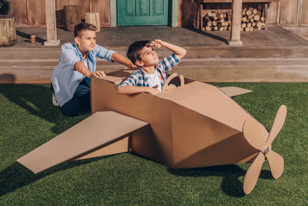 хлопчики грають з картонним літаком
 - Фото, зображення