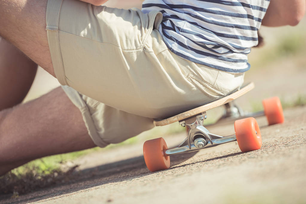 Άνδρας κάθεται στο skateboard - Φωτογραφία, εικόνα