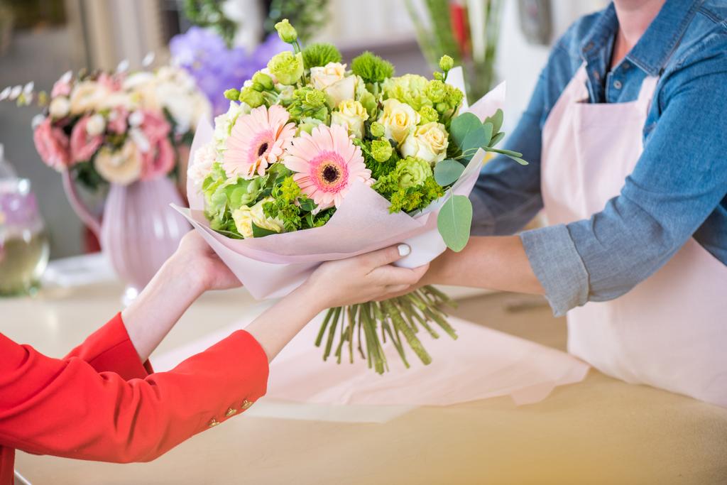 Blumenhändler überreicht Blumenstrauß an Kundin - Foto, Bild