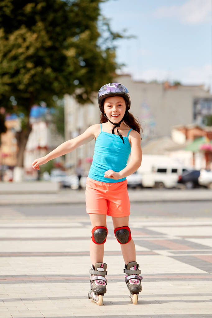 Petite fille mignonne apprenant à patiner à roulettes en plein air sur une belle journée d'été
 - Photo, image
