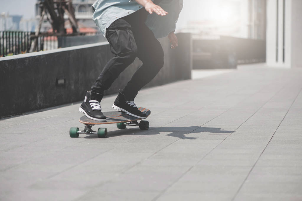 Gros plan des jambes du patineur sur le longboard chevauchant la rue en plein air
 - Photo, image