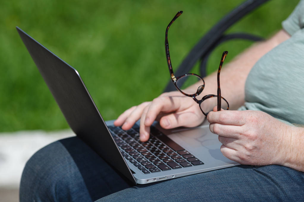 Férfi kezét gépelés-on laptop a parkban - Fotó, kép