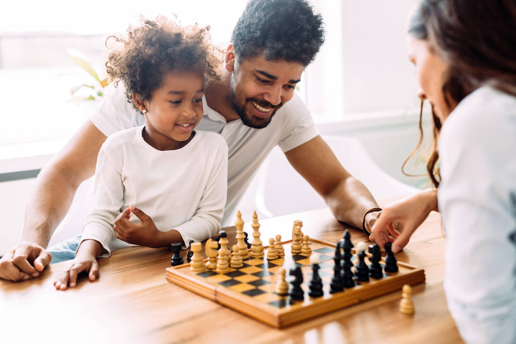 Onnellinen perhe pelaa shakkia yhdessä kotona
 - Valokuva, kuva