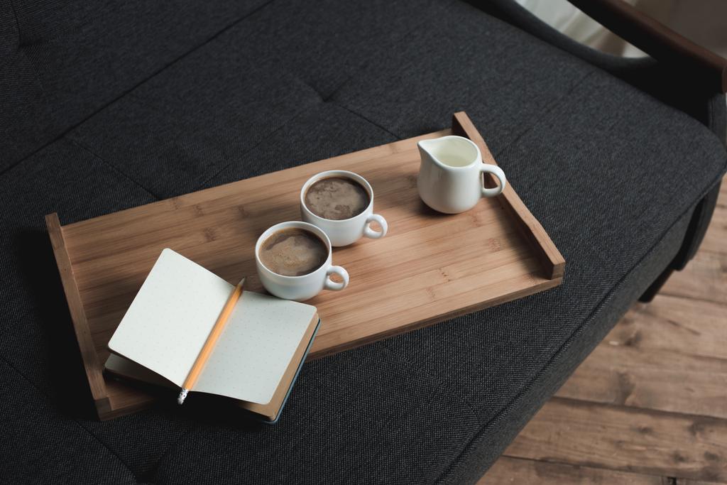 Kaffee, Milchkrug und Notizbuch auf Tablett - Foto, Bild