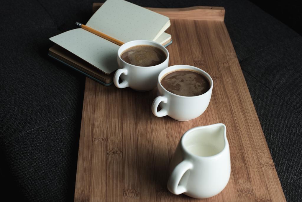 kahvi, kannu maitoa ja muistikirja tarjottimella
 - Valokuva, kuva
