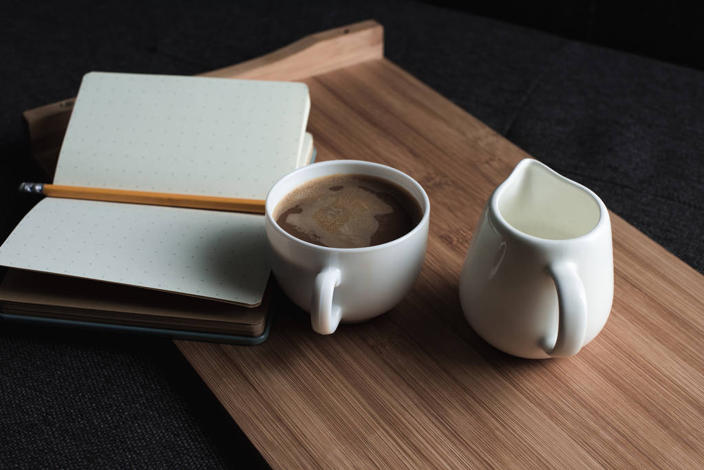 καφέ, κανάτα γάλακτος και σημειωματάριο στο δίσκο - Φωτογραφία, εικόνα
