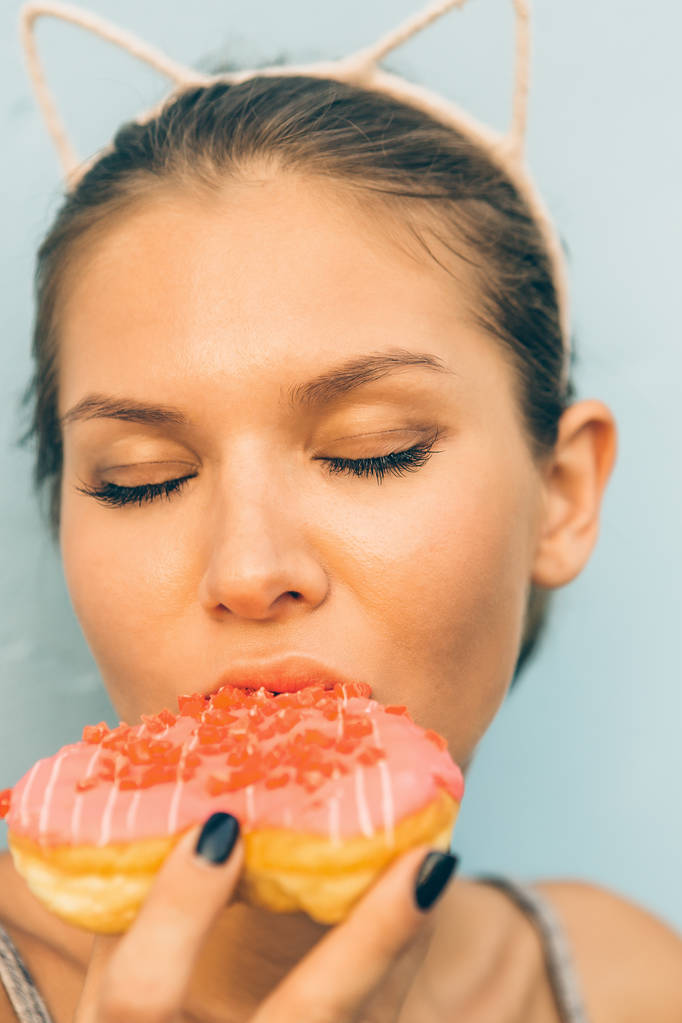 sexy brünette Dame essen süße herzförmige Donut. - Foto, Bild
