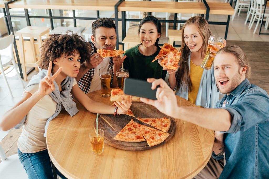 amigos tomando selfie con pizza en la cafetería
 - Foto, imagen
