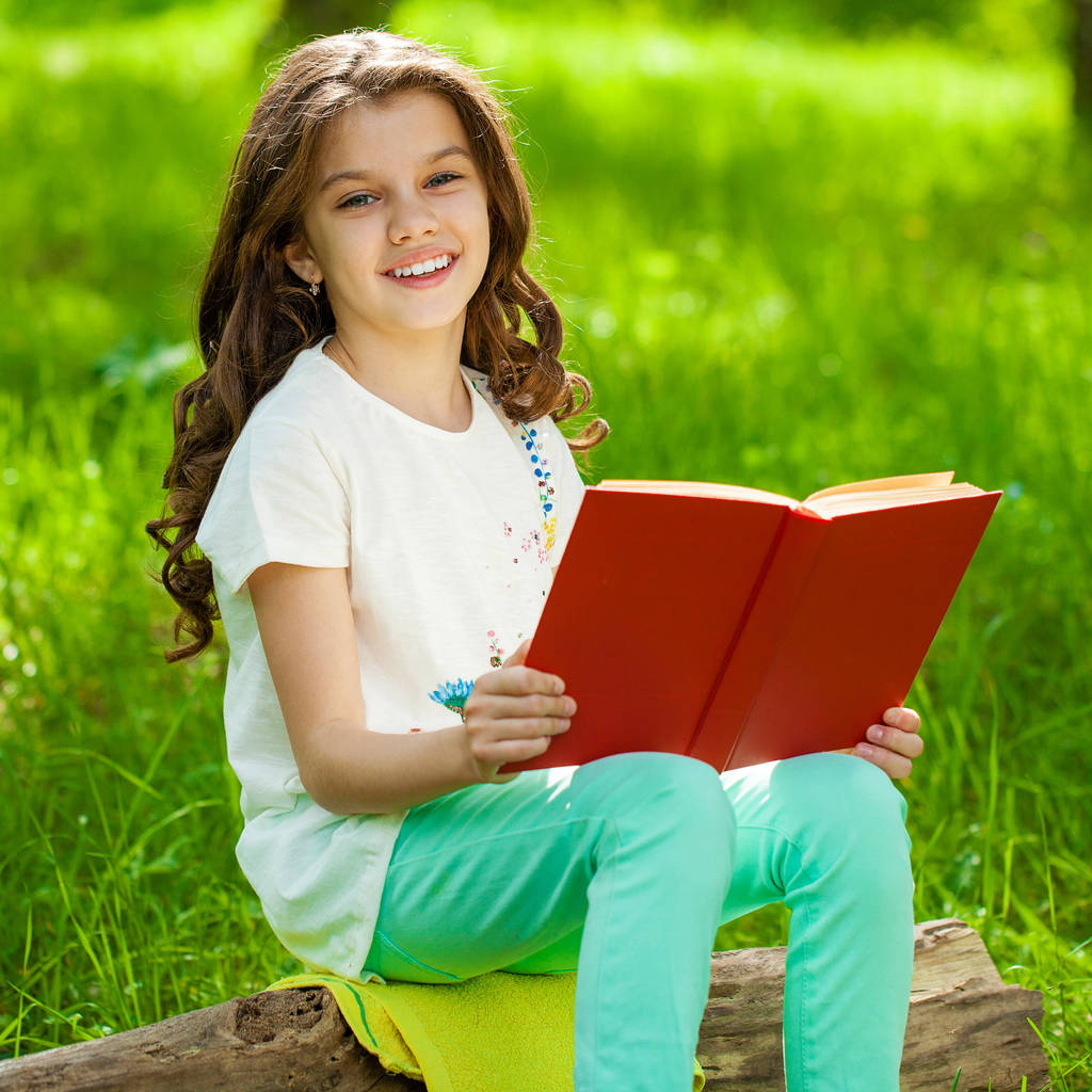 Encantadora niña en el bosque con libro sentado en el tocón del árbol
 - Foto, Imagen