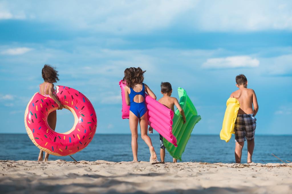 kinderen met opblaasbare matrassen op strand - Foto, afbeelding