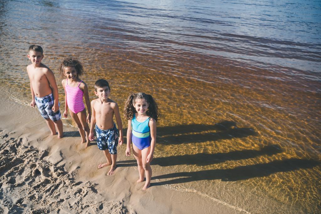 multiculturele kinderen in zwemkleding op strand - Foto, afbeelding