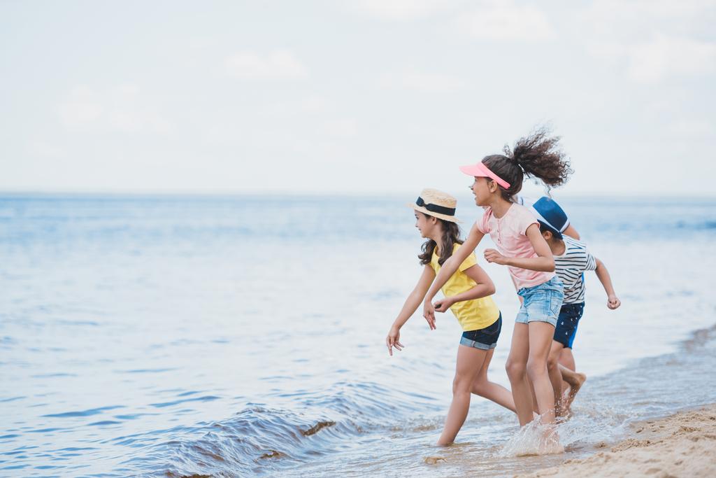 bambini multiculturali che lanciano pietre al mare
 - Foto, immagini