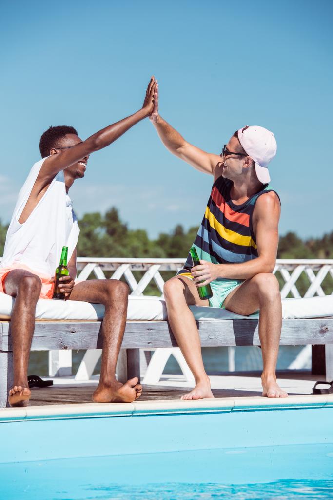 Hombres multiétnicos con cerveza cerca de la piscina
  - Foto, imagen
