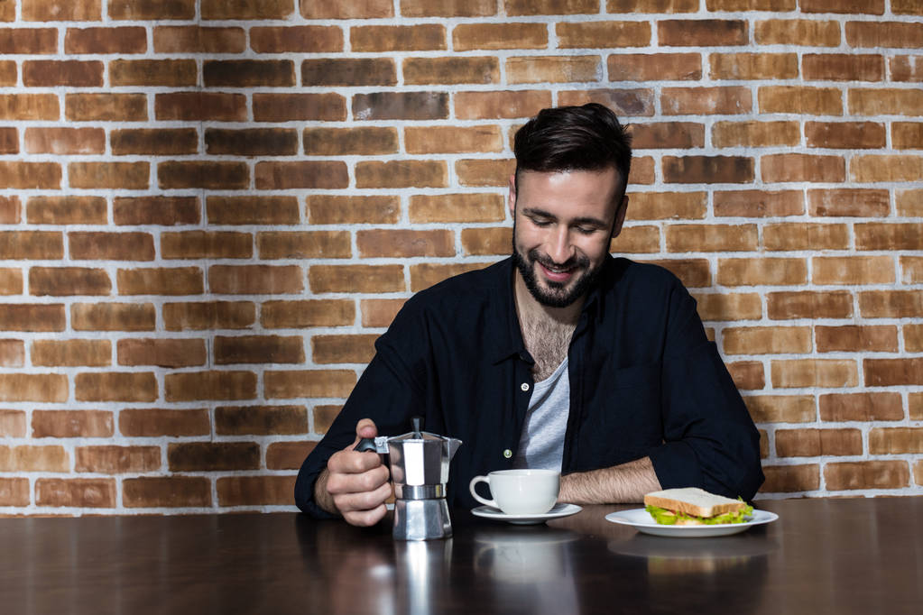 γενειοφόρος νέος άνθρωπος πίνει καφέ - Φωτογραφία, εικόνα