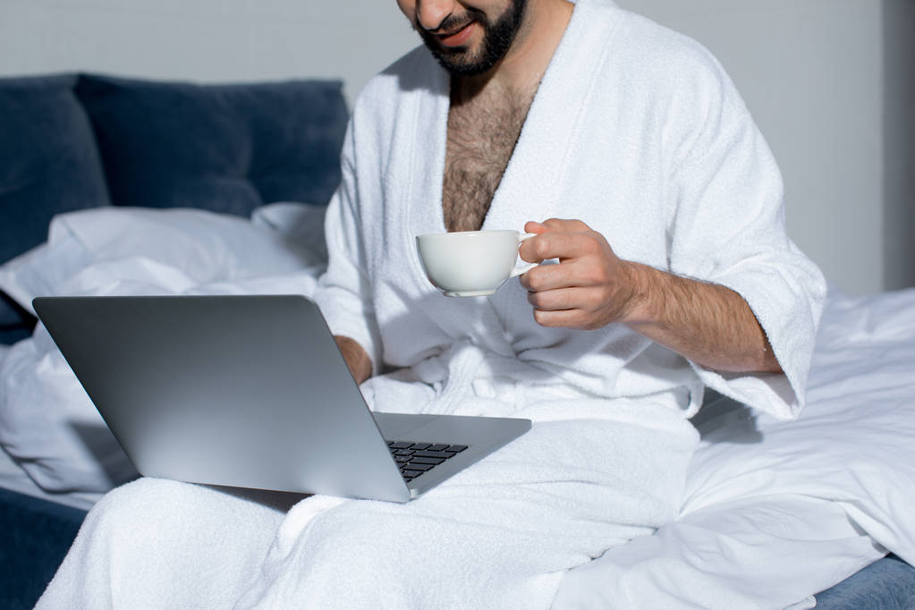 бородатый человек с помощью ноутбука в постели
 - Фото, изображение