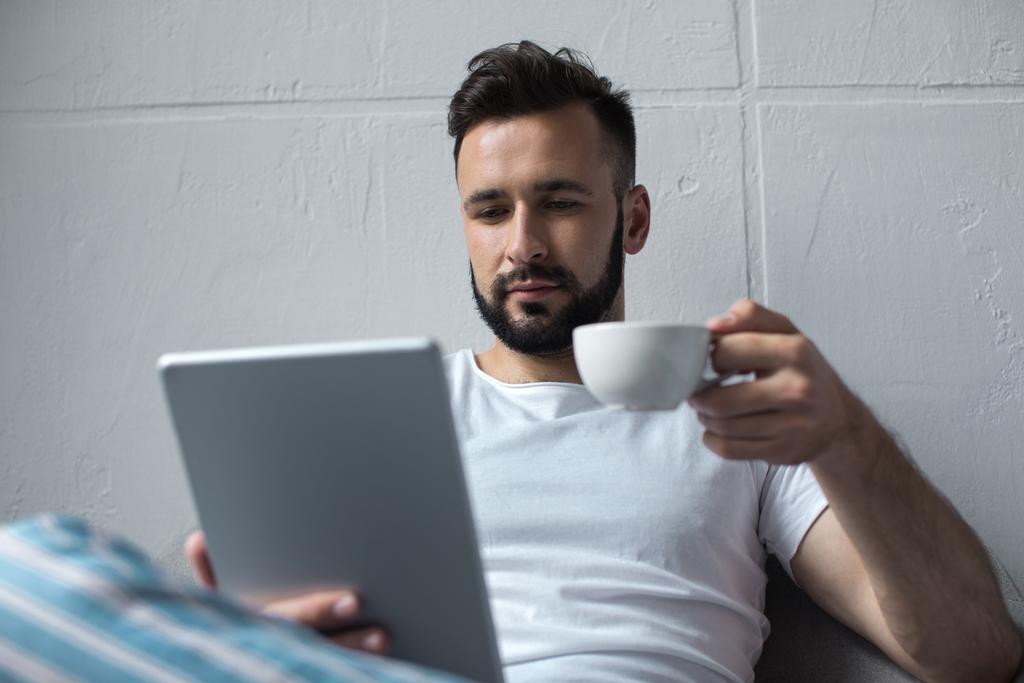 ο άνθρωπος ανάγνωση tablet και πίνοντας τον καφέ - Φωτογραφία, εικόνα