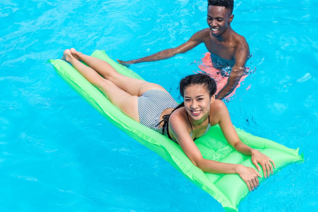 multi-etnisch paar in zwembad in resort - Foto, afbeelding