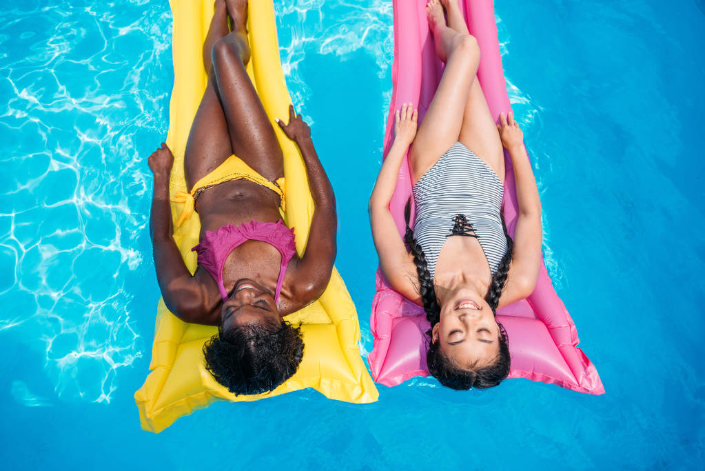 mulheres multiétnicas em colchões infláveis na piscina
 - Foto, Imagem