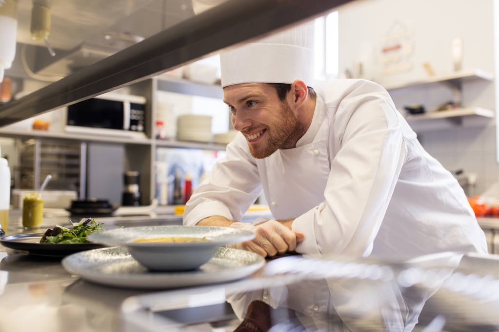onnellinen mieskokki ruoanlaitto ravintolan keittiössä
 - Valokuva, kuva