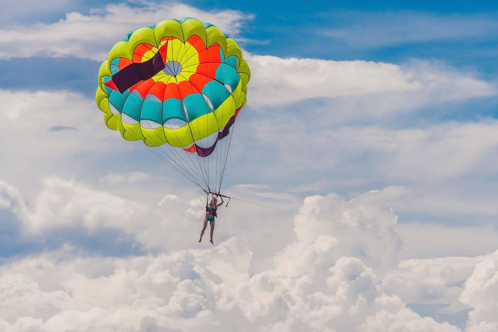 若い女性がパラシュートで飛ぶ  - 写真・画像